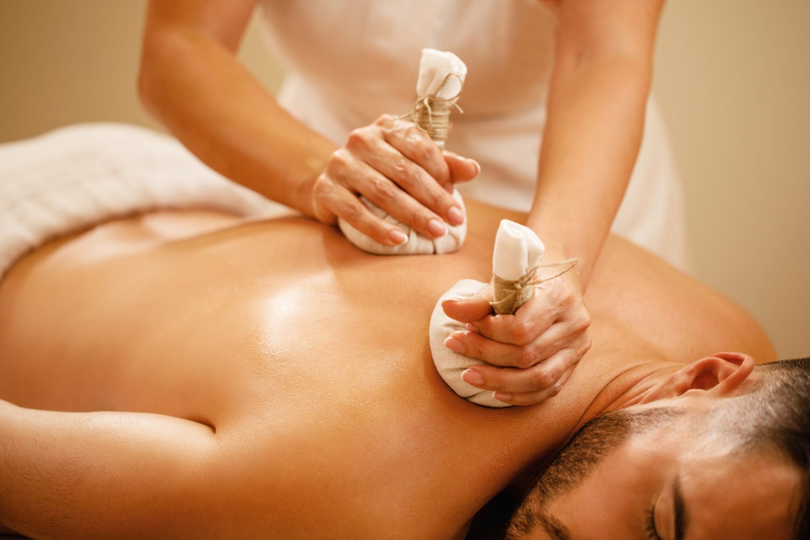 Close-up of man having back massage with herbal compress at the spa.
