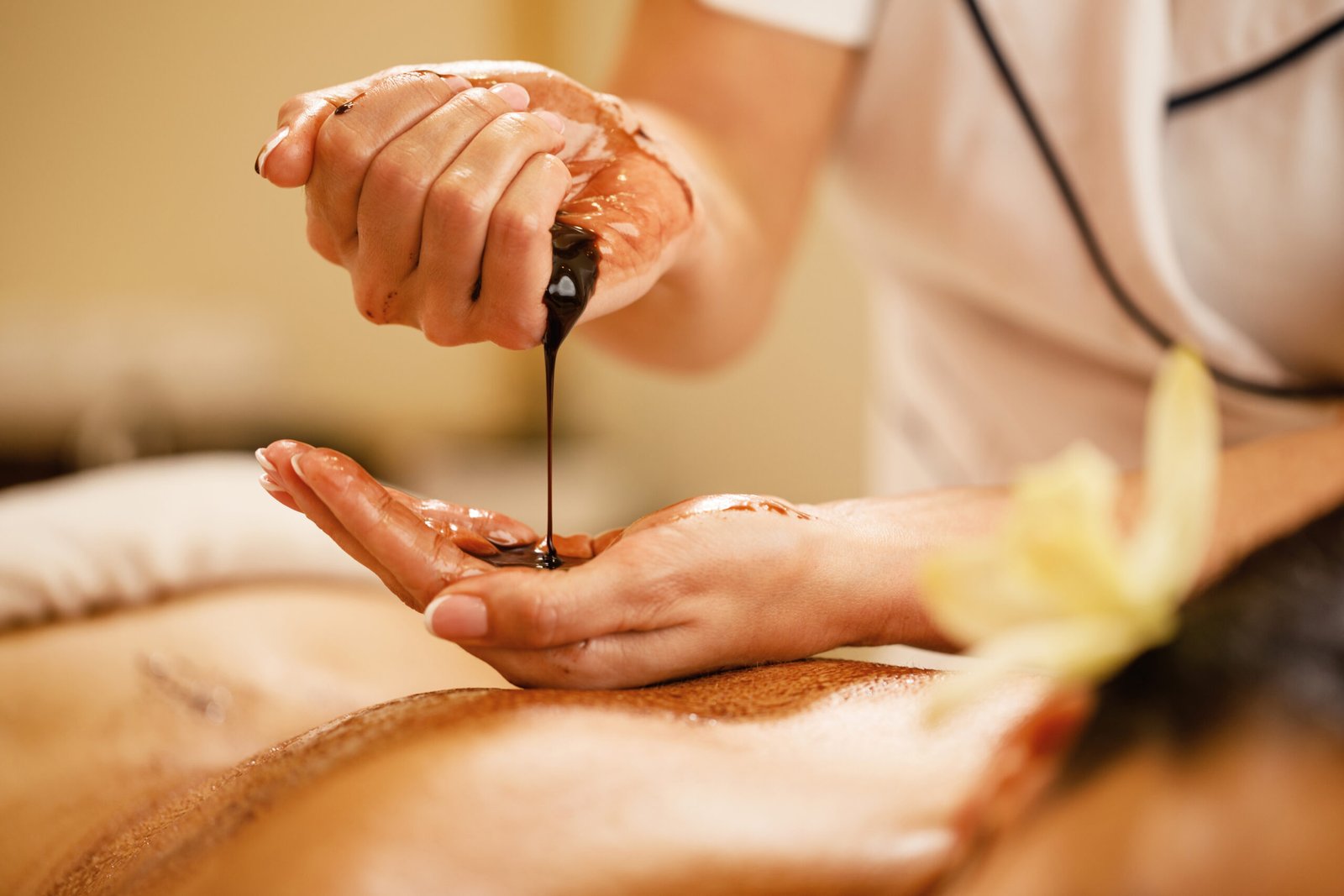 Close-up of therapist preparing for hot chocolate massage at the spa.